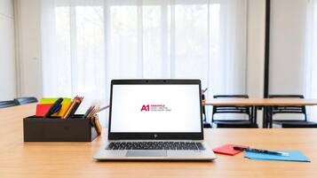 Una computadora portátil sobre un escritorio, con vista a un salón de reuniones al fondo.