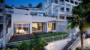 A modern multi-story hotel with a spacious outdoor area, a pool, and a staircase leading to the upper floors.