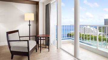 Une chambre d’hôtel avec une grande fenêtre, une chaise, une petite table et un lampadaire.