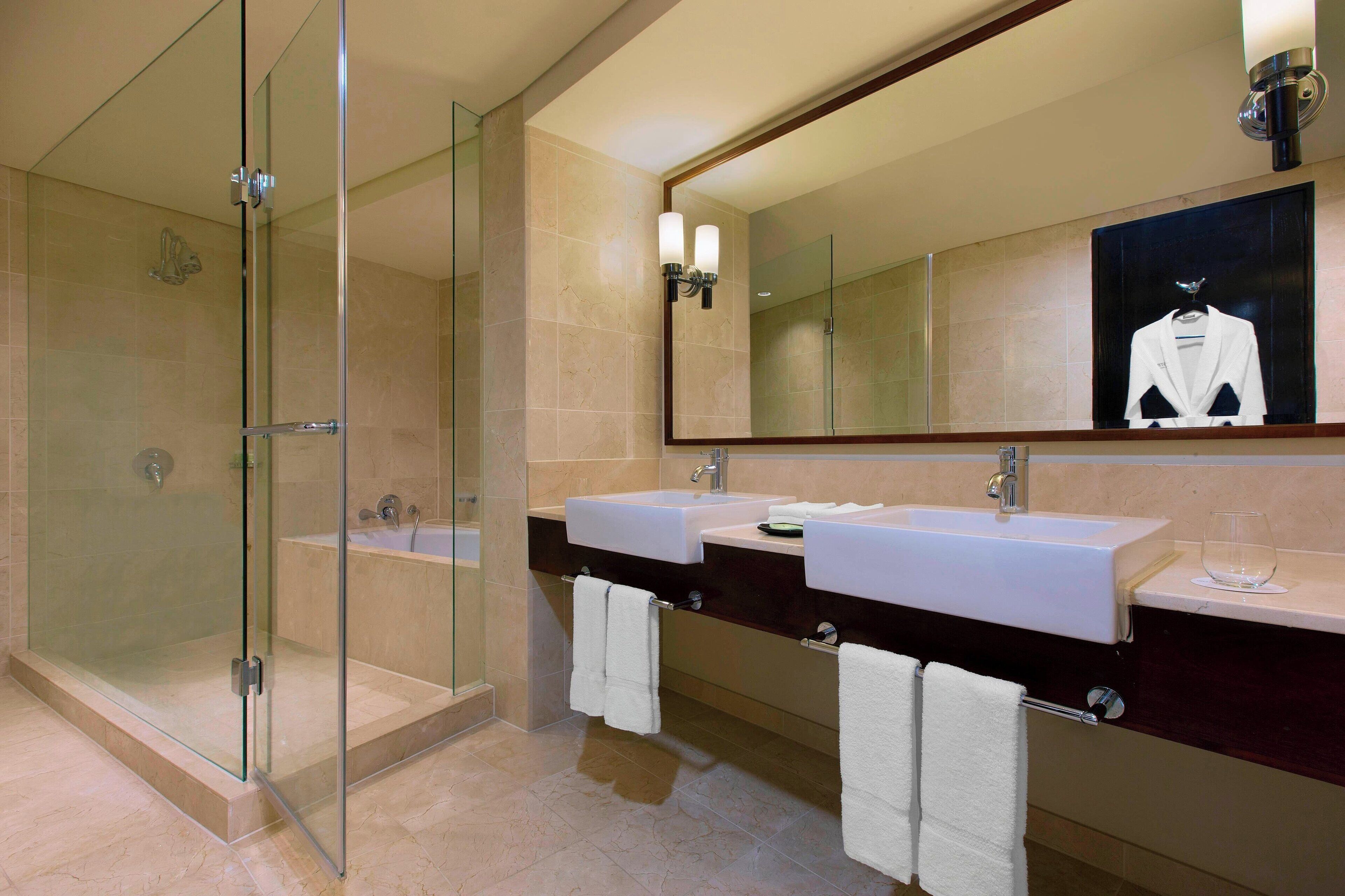 Un baño moderno con dos lavamanos, una cabina de ducha de vidrio y un espejo grande.