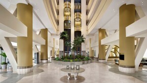 A spacious lobby with high ceilings, large columns, and a central seating area.