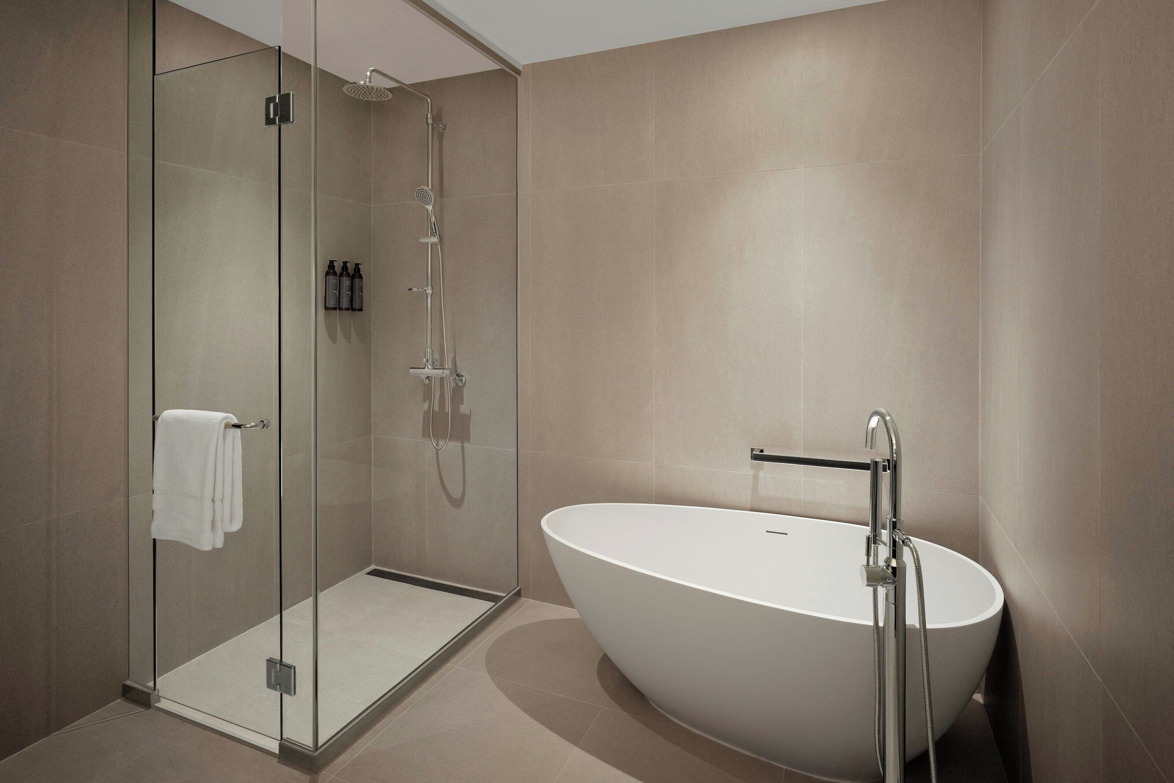 A modern bathroom with a glass-enclosed shower, a freestanding bathtub, and a glass door.