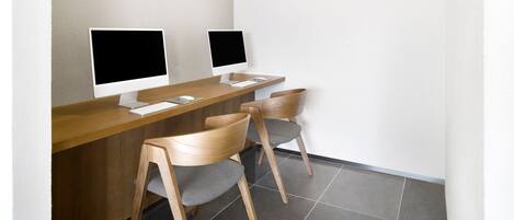Un espacio de trabajo moderno con dos computadoras de escritorio, un escritorio de madera y dos sillas.