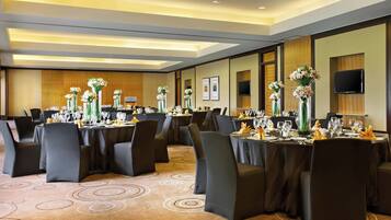 A conference room with round tables, black chairs, and floral centerpieces.