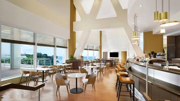 A spacious dining area with high ceilings, large windows, and a modern bar area.
