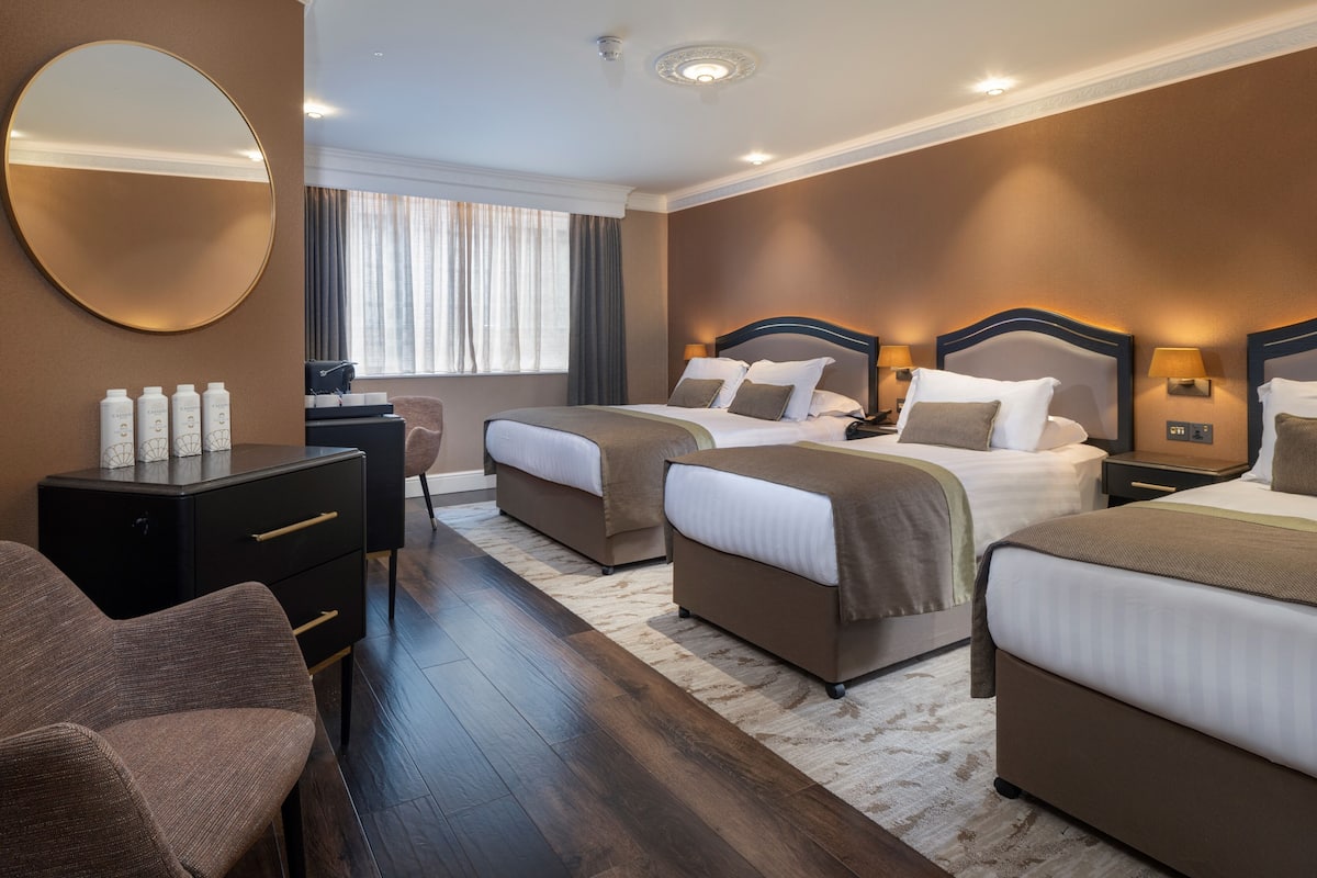 Una habitación de hotel con dos camas, un escritorio, una silla y un espejo grande.