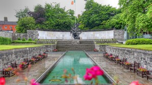 A memorial with a central pool, benches, and a statue.