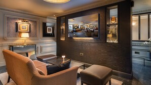 A modern lobby with a sofa, ottoman, and a fireplace.