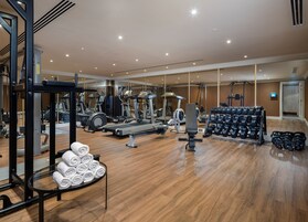 Un gimnasio espacioso con diversos equipos de ejercicio, incluyendo cintas de correr, elípticas y pesas libres.