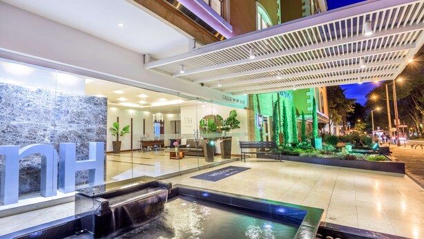 Un hall d’hôtel comprenant un comptoir d’accueil, un espace salon et un élément décoratif aquatique.