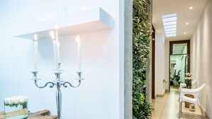 Un intérieur moderne agrémenté d’un chandelier, d’un vase en verre rempli de fleurs et d’un mur végétal.