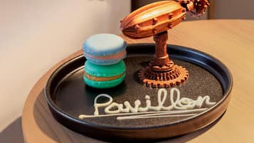 A tray with macarons and a chocolate gear, and the word 'Pavillon' written on it.