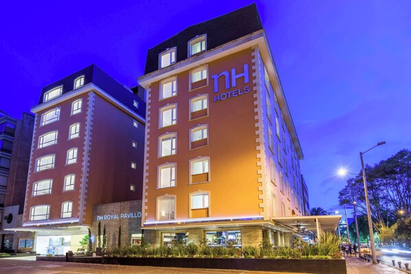 Een hotel met meerdere verdiepingen en een goed verlichte ingang.