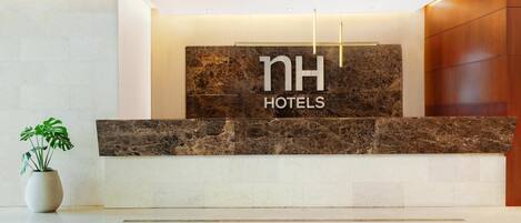 Un comptoir d’accueil avec un plateau en marbre et une enseigne indiquant « NH HOTELS ».