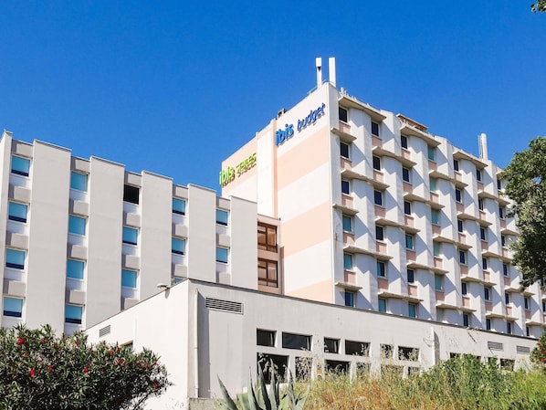 Un hôtel à plusieurs étages, reconnaissable à son grand panneau « ibis budget », doté de balcons et d’une façade sobre.