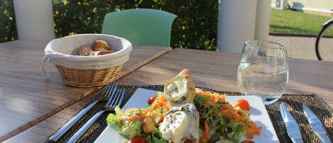 A table set with a salad, a basket of bread, and a glass of water.