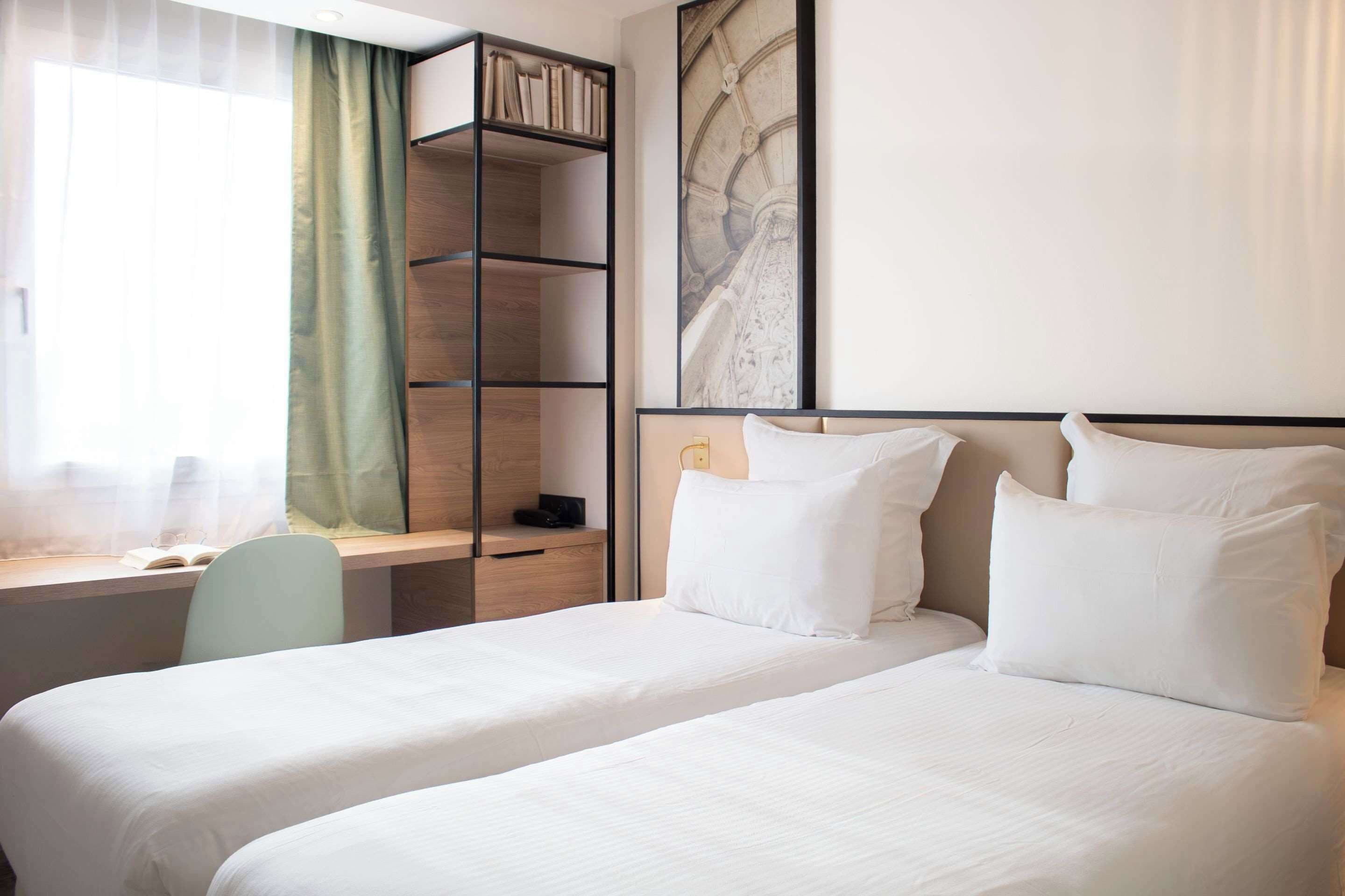 A hotel room with a bed, a desk, and a bookshelf.