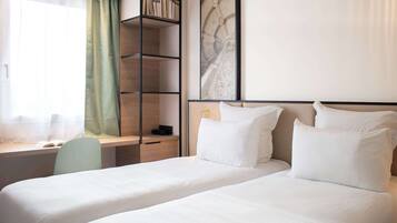 A hotel room with a bed, a desk, and a bookshelf.