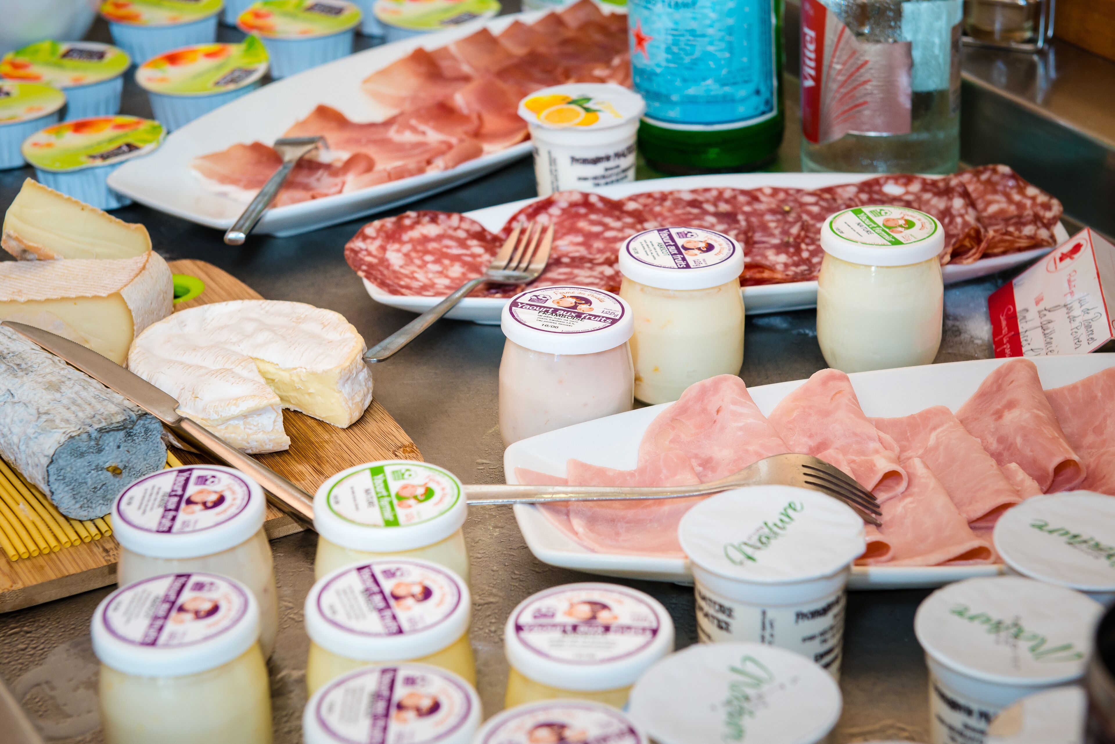 Diverse kazen, vleeswaren en potten met ingemaakte producten op een tafel.