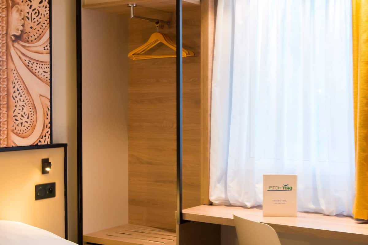 Une chambre d’hôtel avec un lit, un bureau et un dressing.