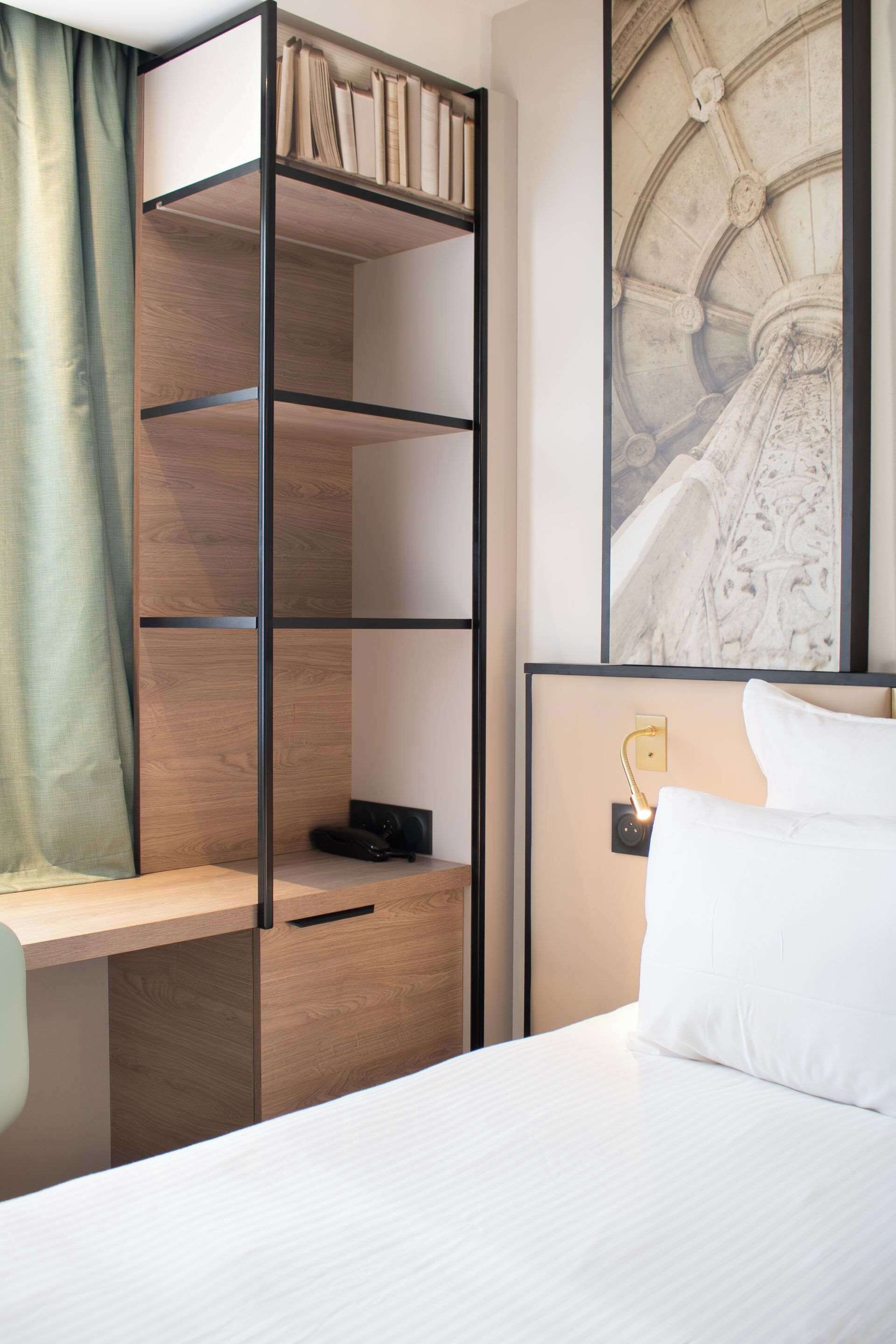 A bedroom with a bed, a desk, and a built-in shelving unit.