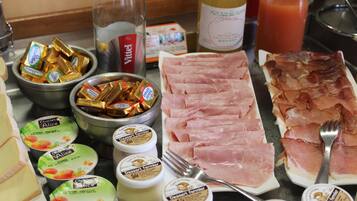 Ein Frühstücksbuffet mit verschiedenen Speisen, darunter Schinken, Käse und Schokoladentafeln.