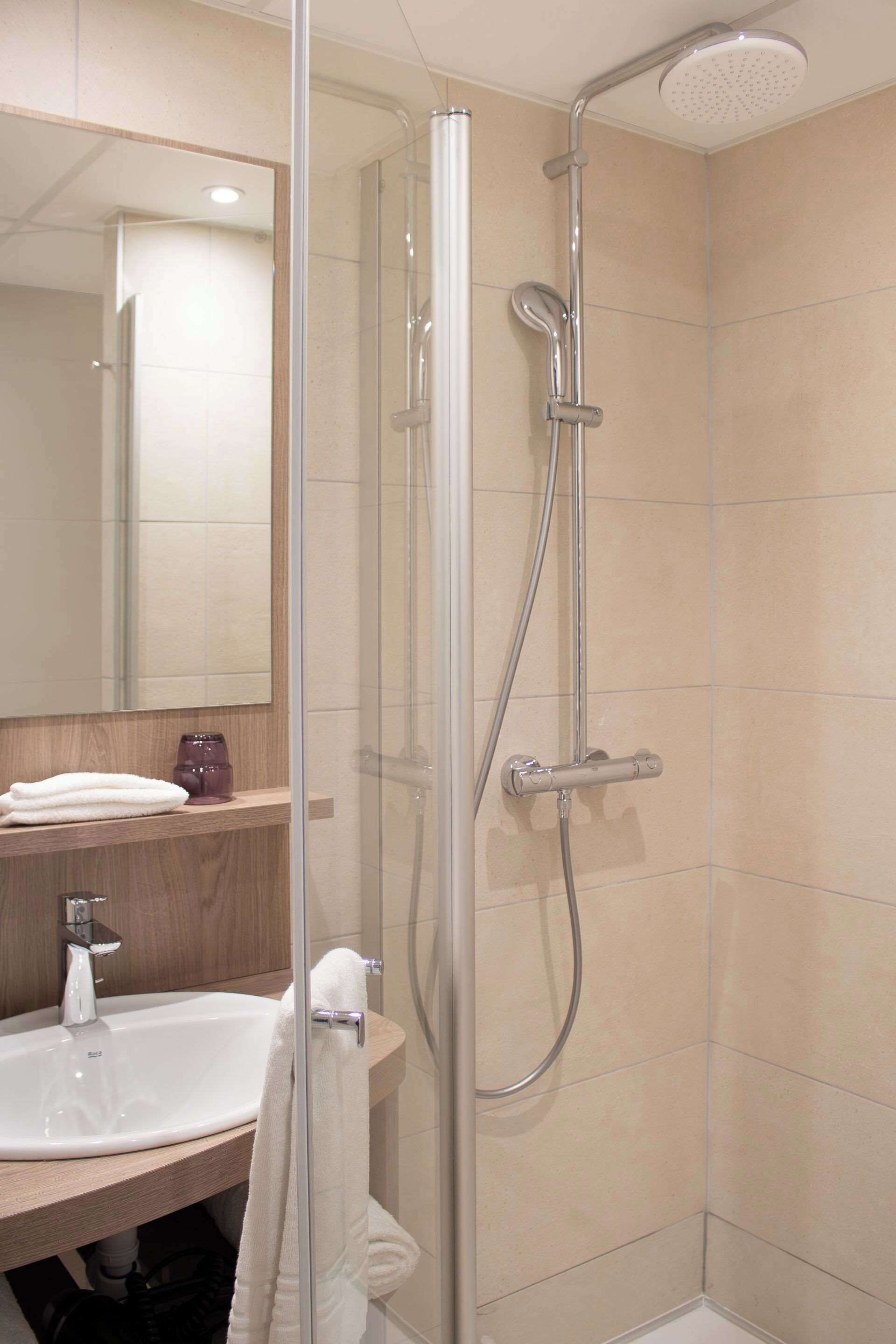 A modern bathroom with a glass-enclosed shower, a sink, and a mirror.