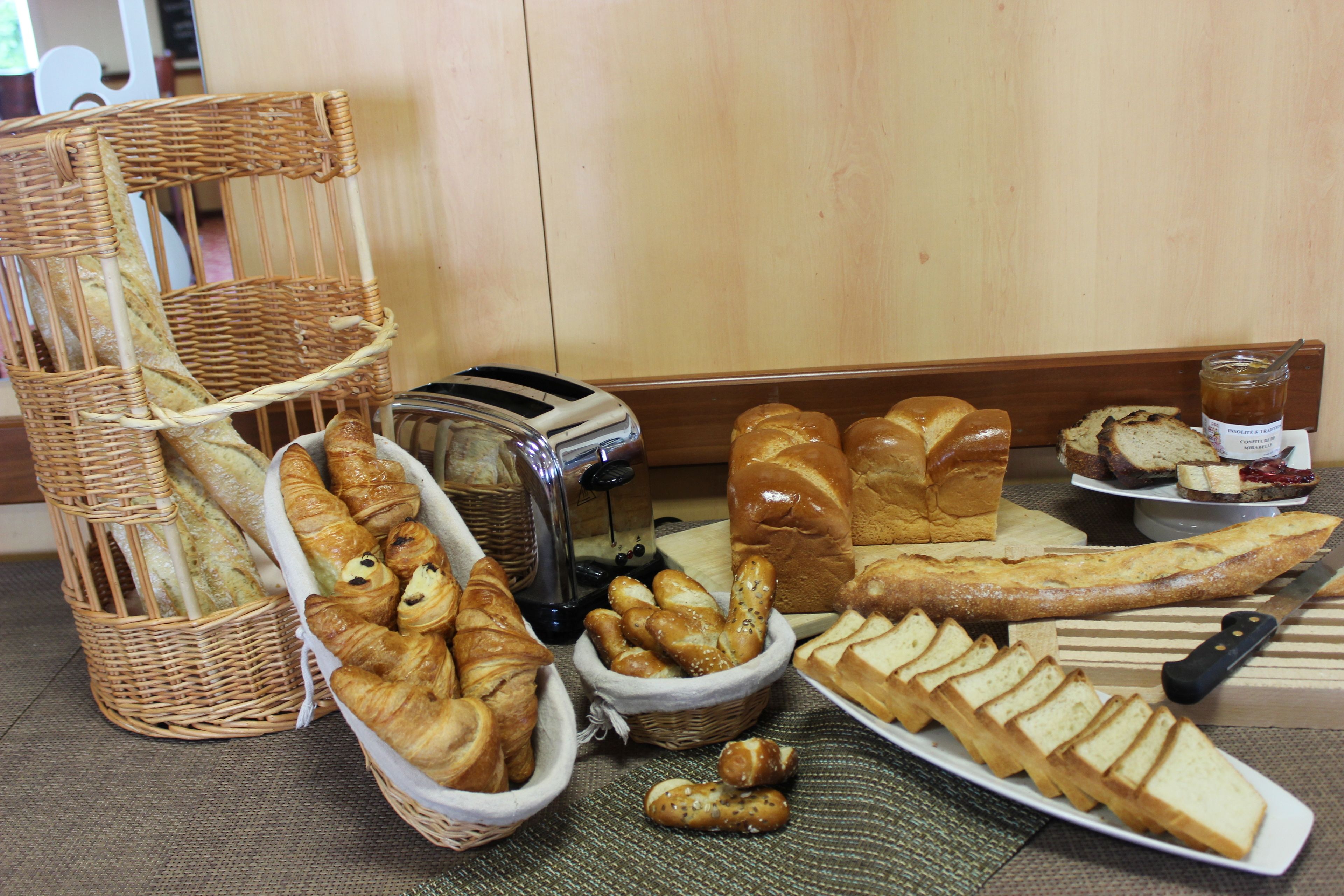 A variety of breads and pastries on a table, including croissants, baguettes, and a loaf of bread.
