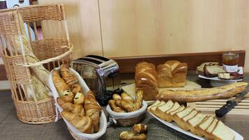 Variedad de panes y pasteles en una mesa, incluyendo croissants, baguettes y una hogaza de pan.