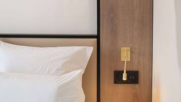 Een hotelkamer met een bed, een nachtkastje met een lamp en een houten paneelwand.