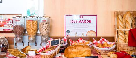 Un bufé de desayuno con diversos alimentos y un cartel que indica el compromiso de la panadería con la calidad artesanal.