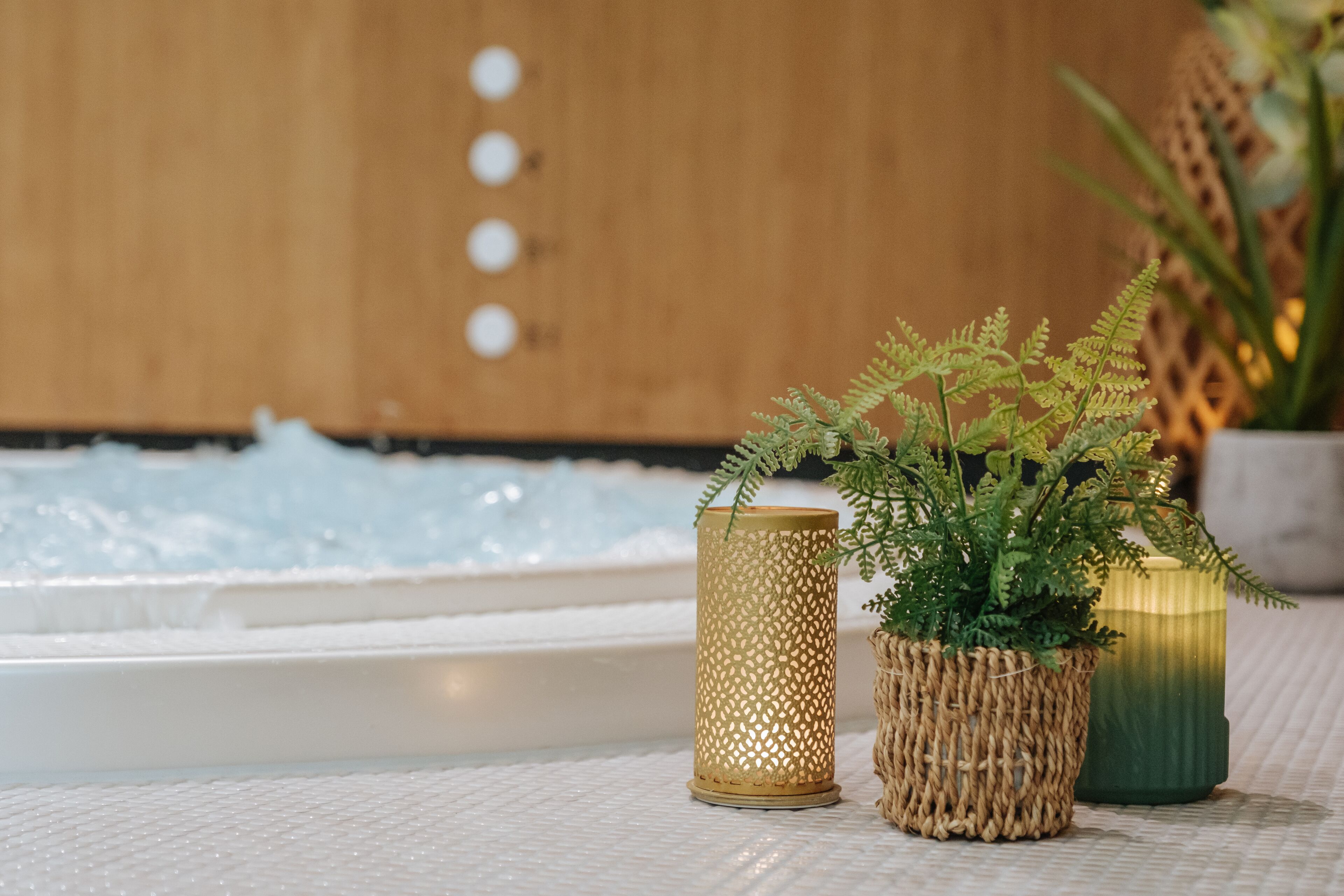 Un espace bien-être comprenant un bain à remous, une bougie décorative et une plante en pot.