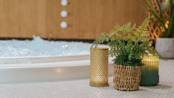 Un espace bien-être comprenant un bain à remous, une bougie décorative et une plante en pot.