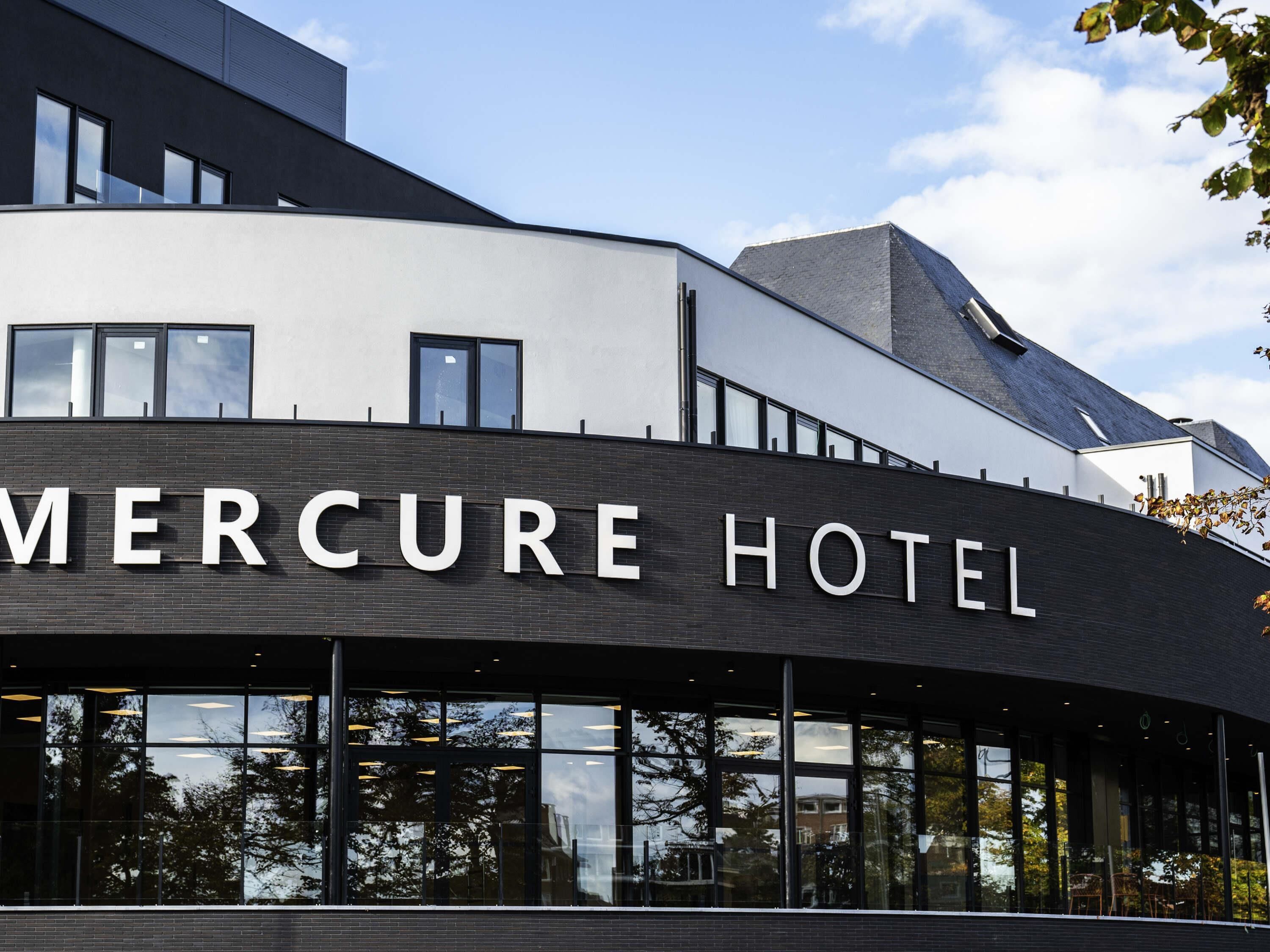 Een modern gebouw met het bord 'Mercure Hotel', wat een hotel aangeeft.