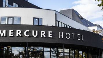 Een modern gebouw met het bord 'Mercure Hotel', wat een hotel aangeeft.
