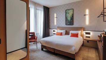A hotel room with a large bed, bedside tables, a chair, and a painting on the wall.