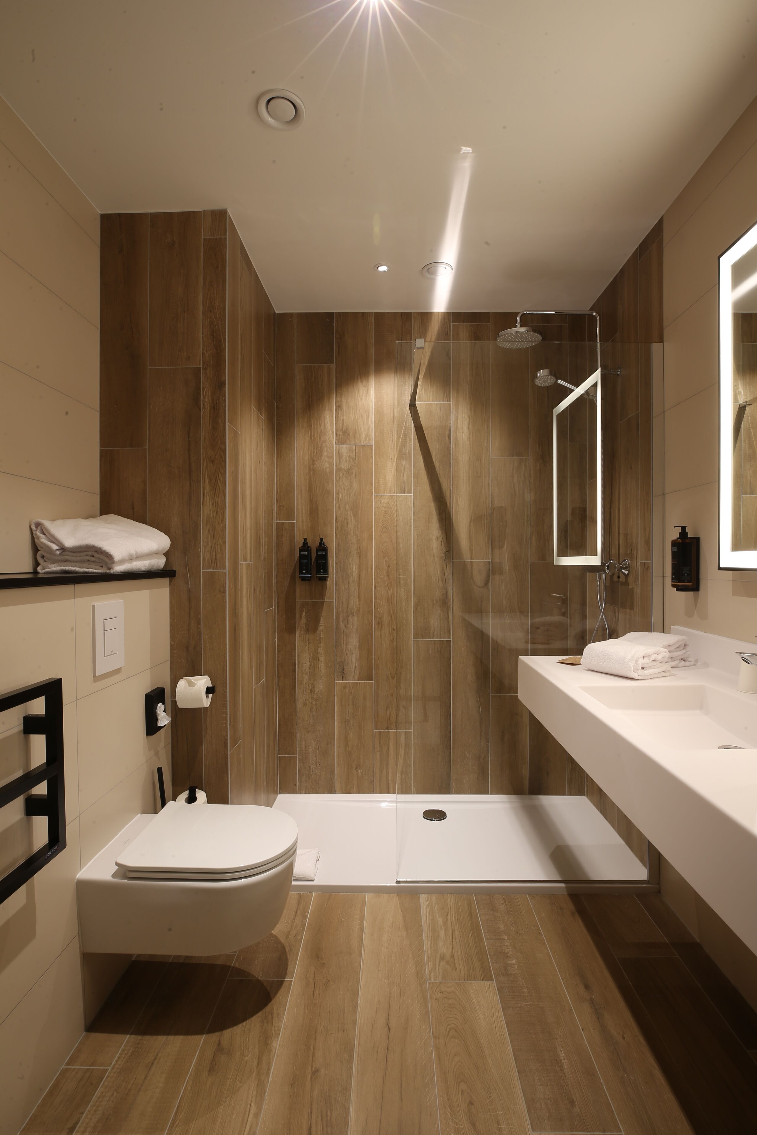 Een moderne badkamer met douche, toilet en wastafel.