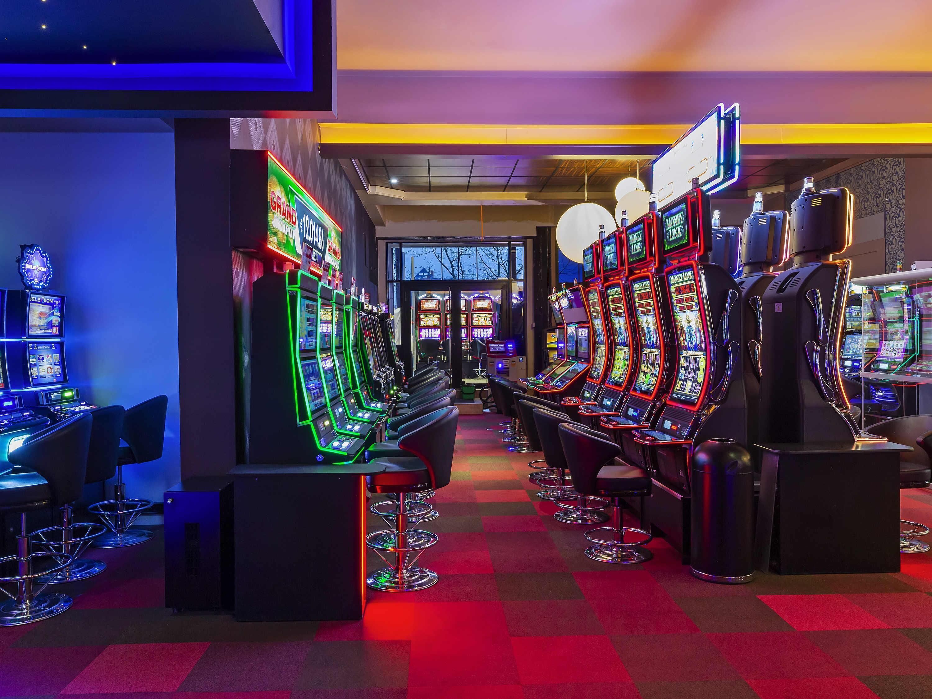 Una hilera de máquinas tragamonedas con luces de neón, taburetes de bar y un suelo a cuadros.