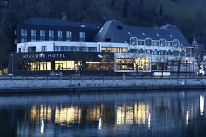 A modern hotel with a reflective water body in front, featuring a prominent sign for the Mercure Hotel.
