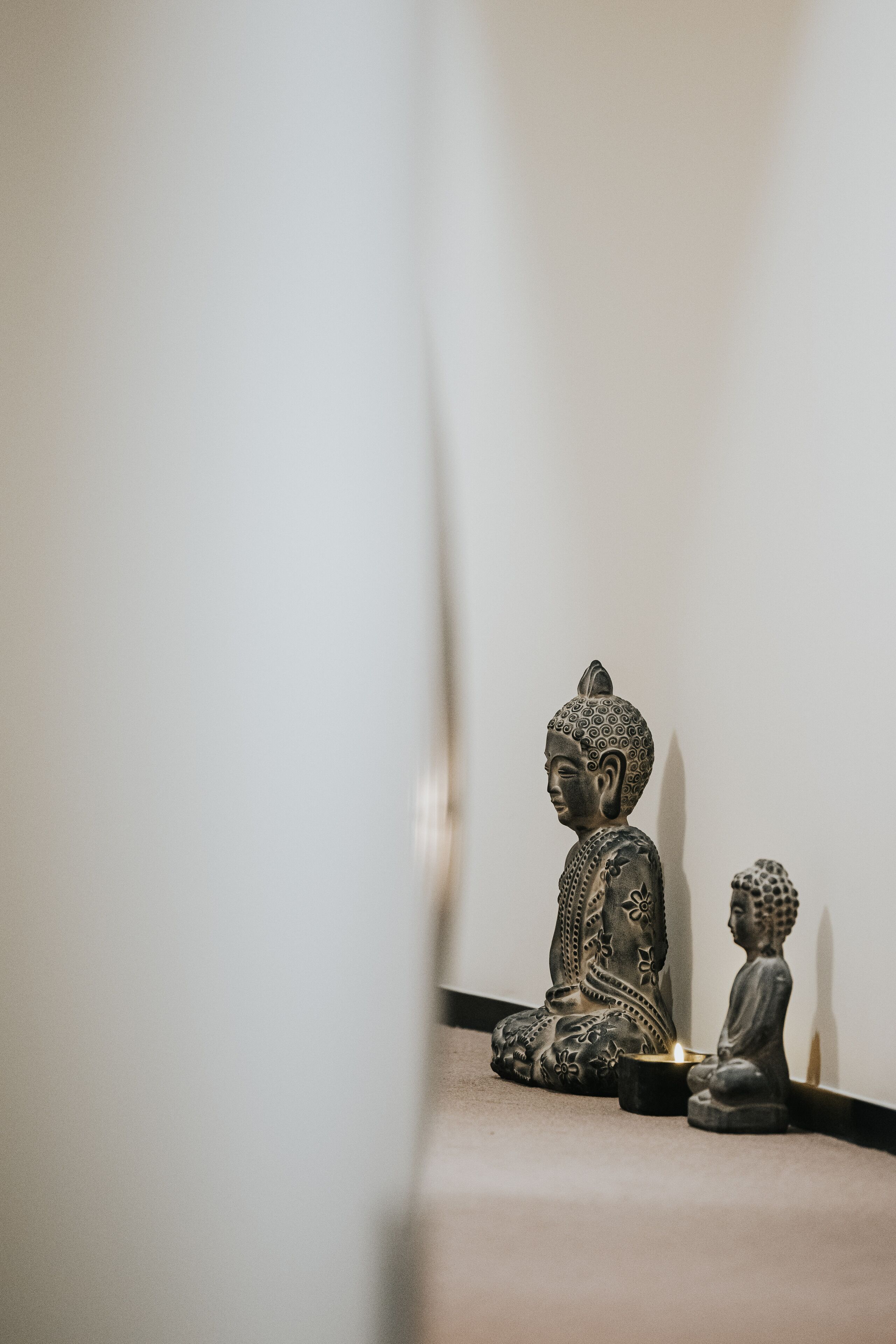 A room with a Buddha statue and a small Buddha statue on the floor.