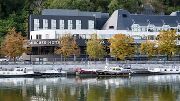 Een modern hotel met zichtbare naam, aangemeerde boten en een ligging aan het water.