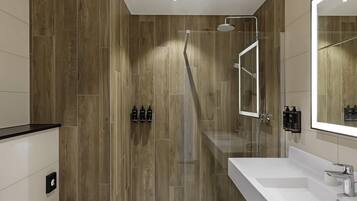 Een moderne badkamer met een houten wand, een douche, een grote spiegel en een wit wastafel.