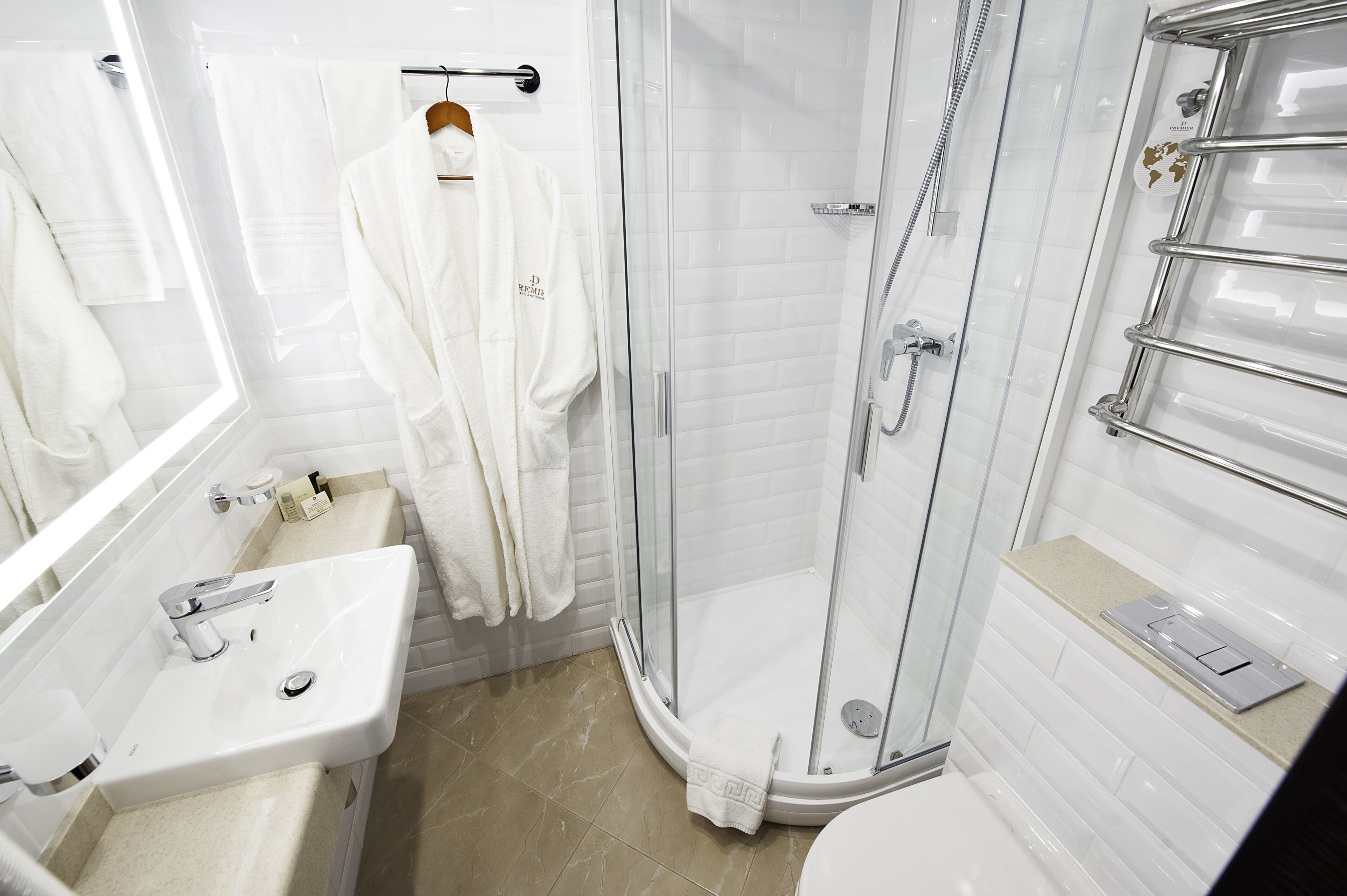 A modern bathroom with a glass-enclosed shower, a white sink, and a towel rack.