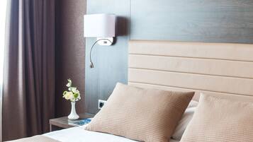 A hotel room with a bed, a nightstand, a lamp, and a vase with flowers.