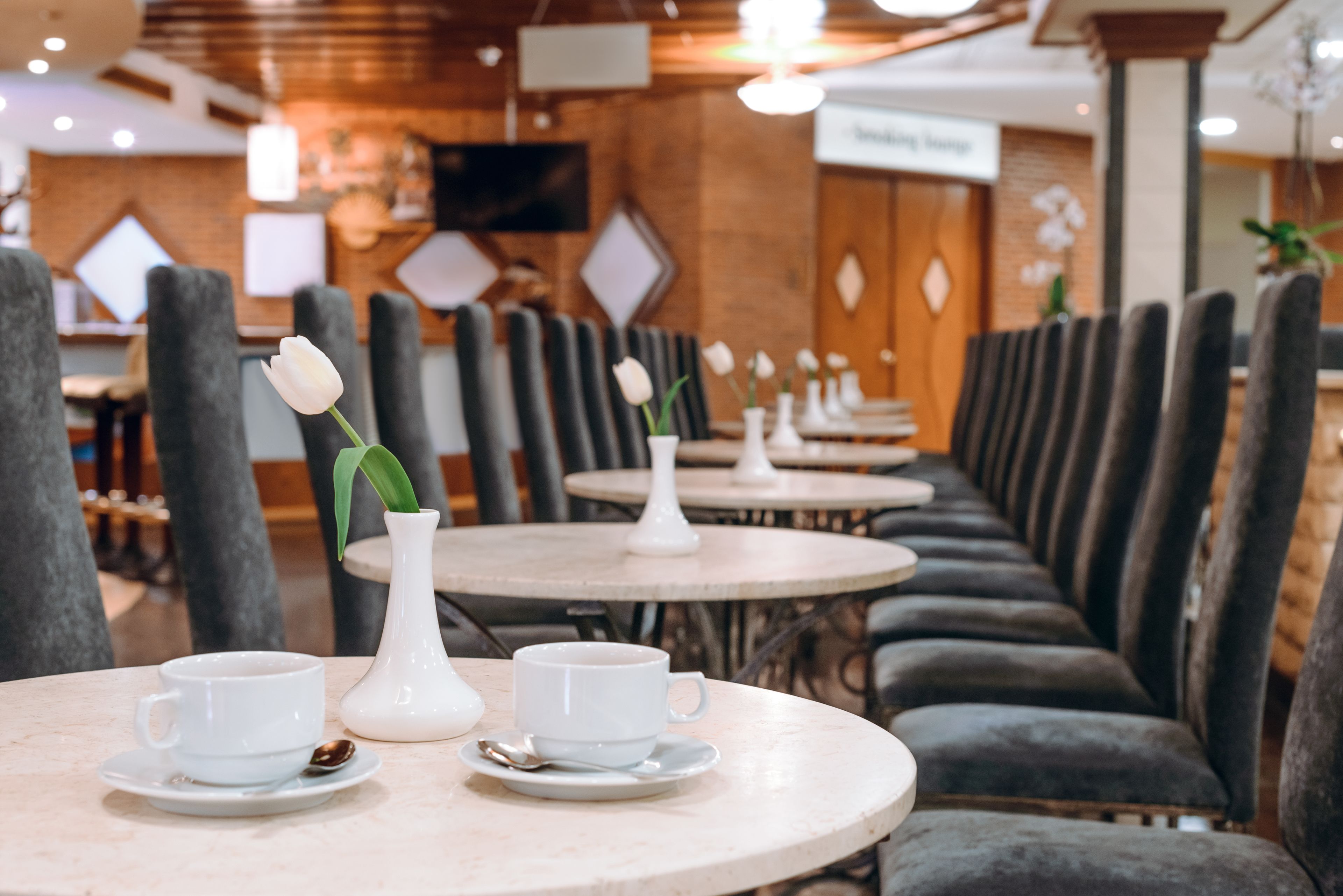 Een restaurant met ronde tafels en grijze, beklede zitbanken.