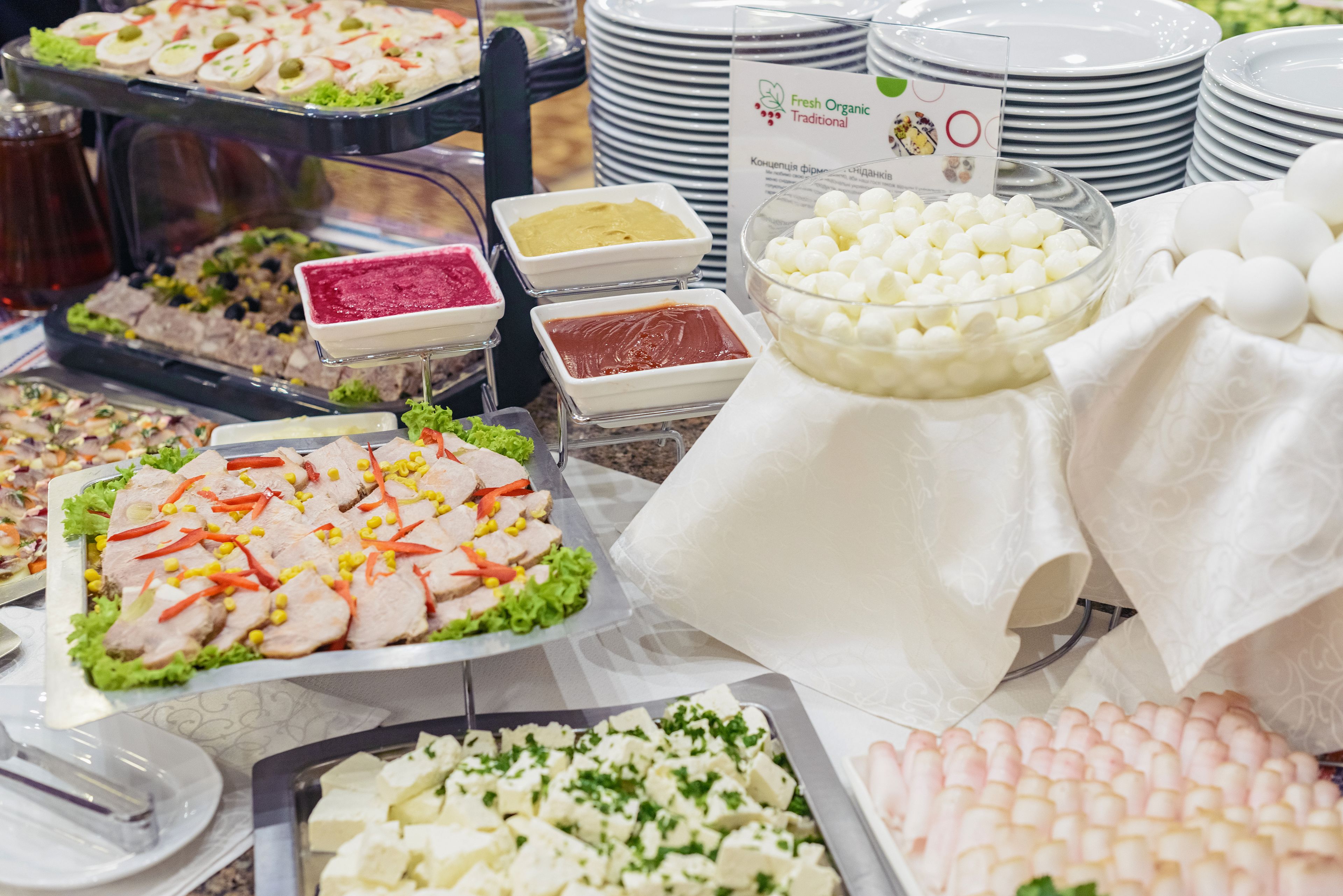 Een buffet met diverse gerechten, waaronder een schaal met vleesschijfjes en groenten, diverse bakjes met dips en een kom met marshmallows.
