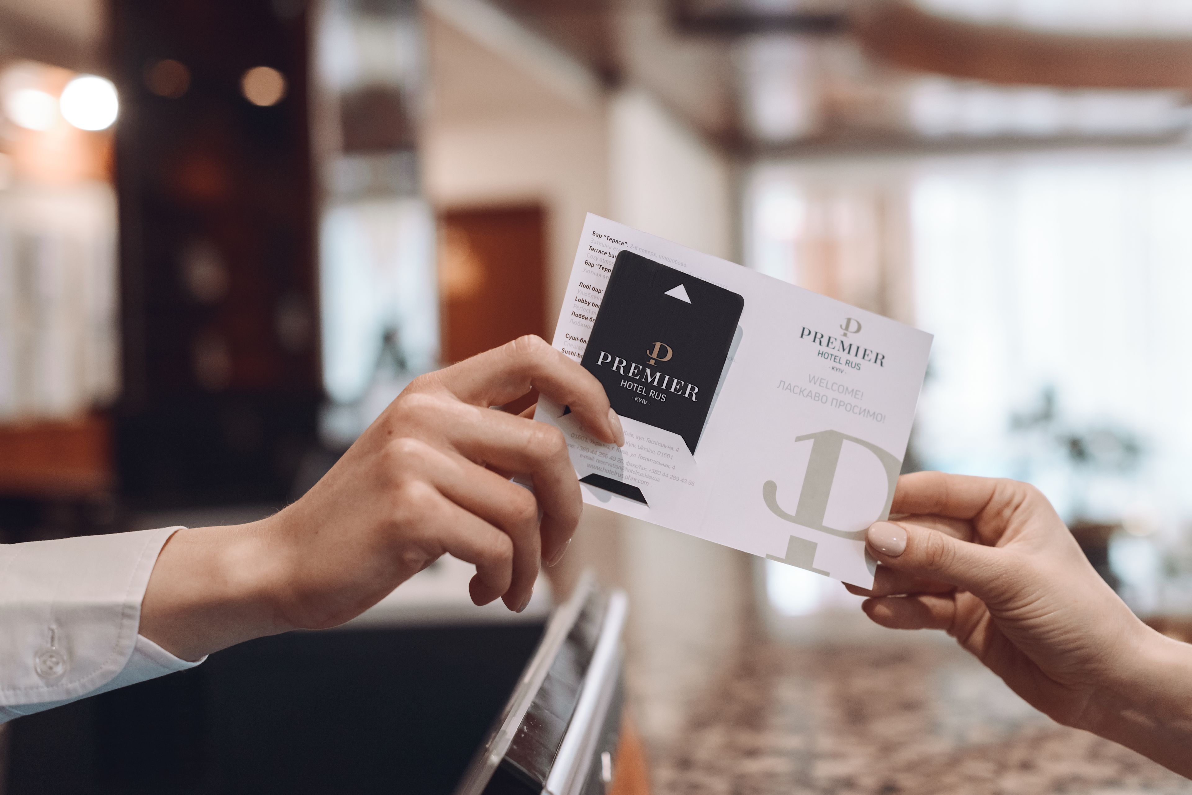 Una persona sosteniendo una tarjeta de presentación que dice "Premier Hotel Rus".