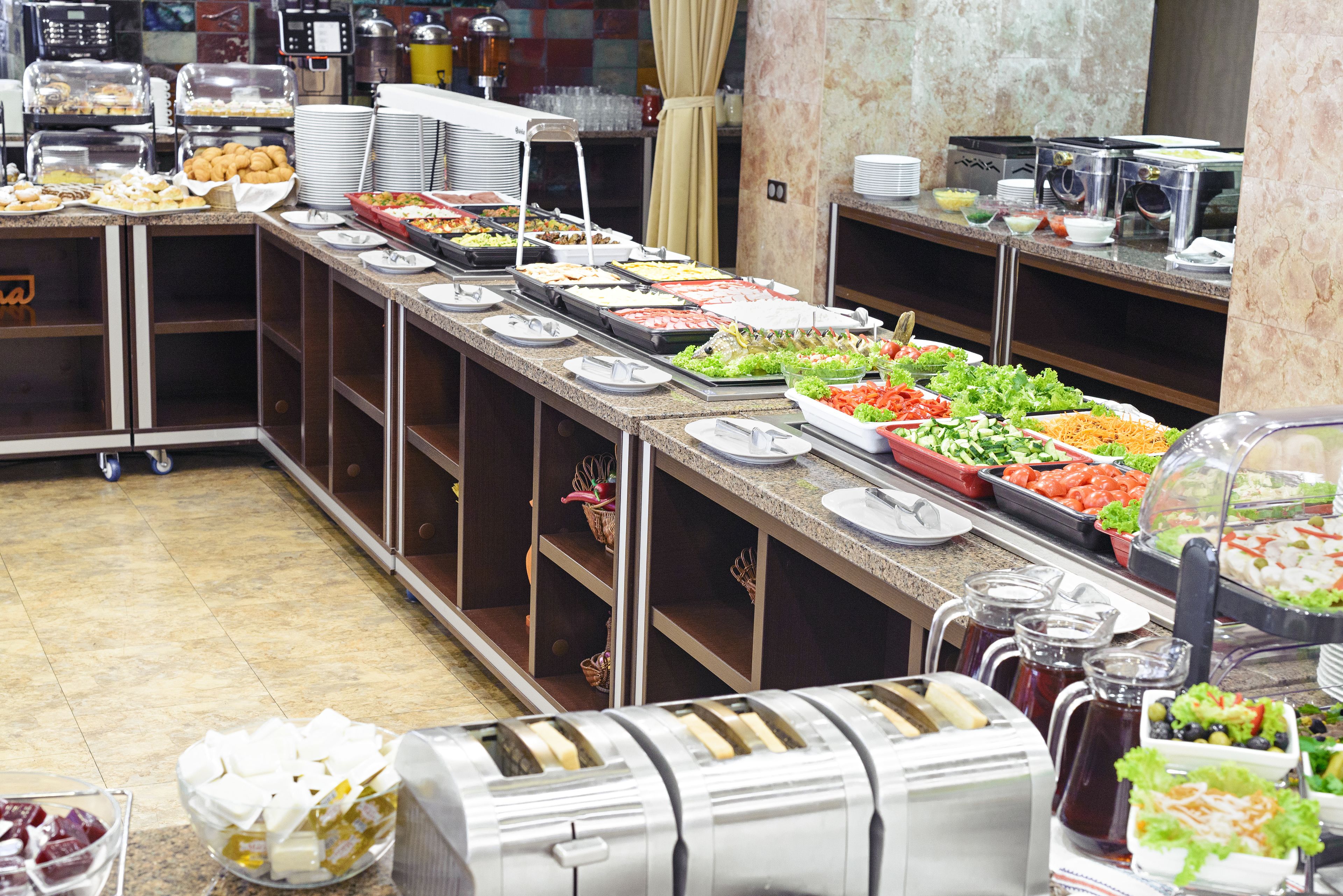 A buffet with various food options, including salads, fruits, and hot dishes.