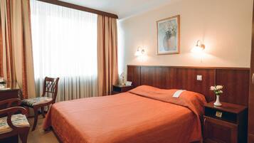 Une chambre d’hôtel avec un grand lit, un bureau avec une chaise, une table de chevet et un tableau au mur.
