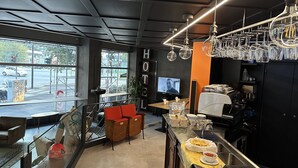 A modern hotel lobby with a bar area, seating, and a large window overlooking the street.